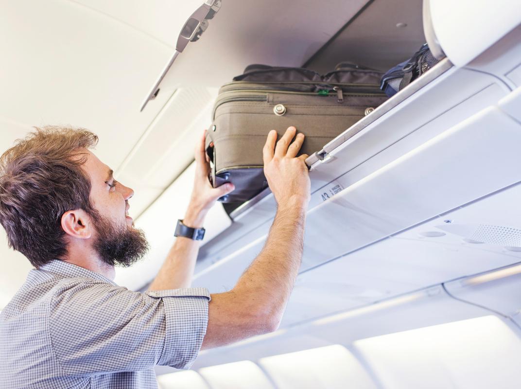 Fluggast schiebt Gepäck in Ablagefach