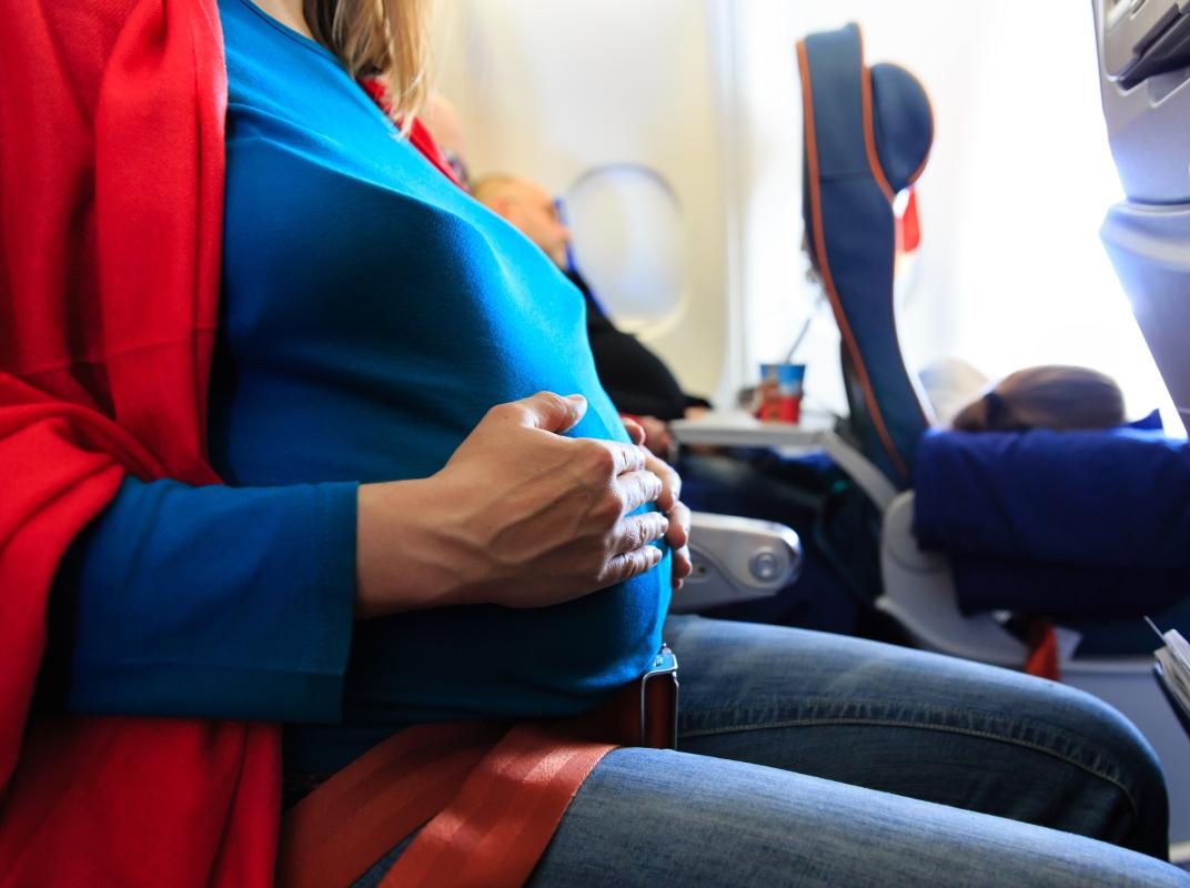 Seitlicher Blick auf eine schwangere Frau in einem Flugzeugsitz