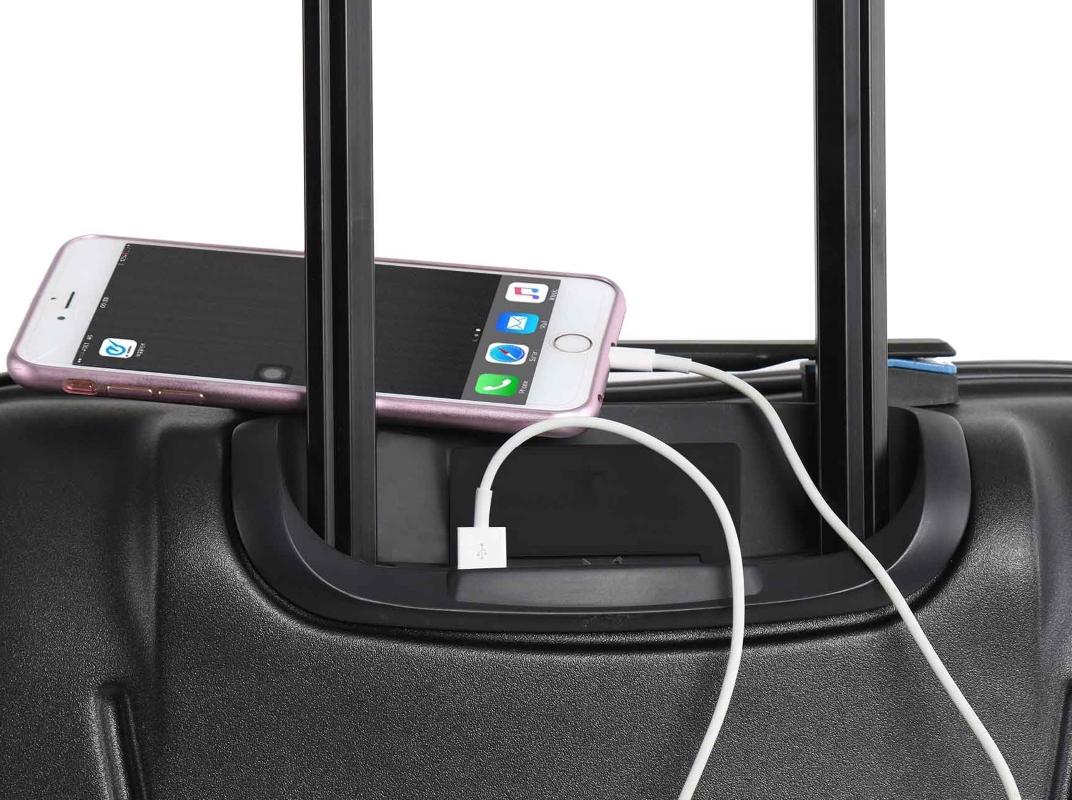 Trolley-Koffer, auf dem ein Handy liegt. Handy ist über Ladekabel mit Koffer verbunden.