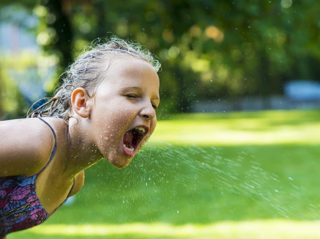 Mädchen trinkt Wasser aus Leitung