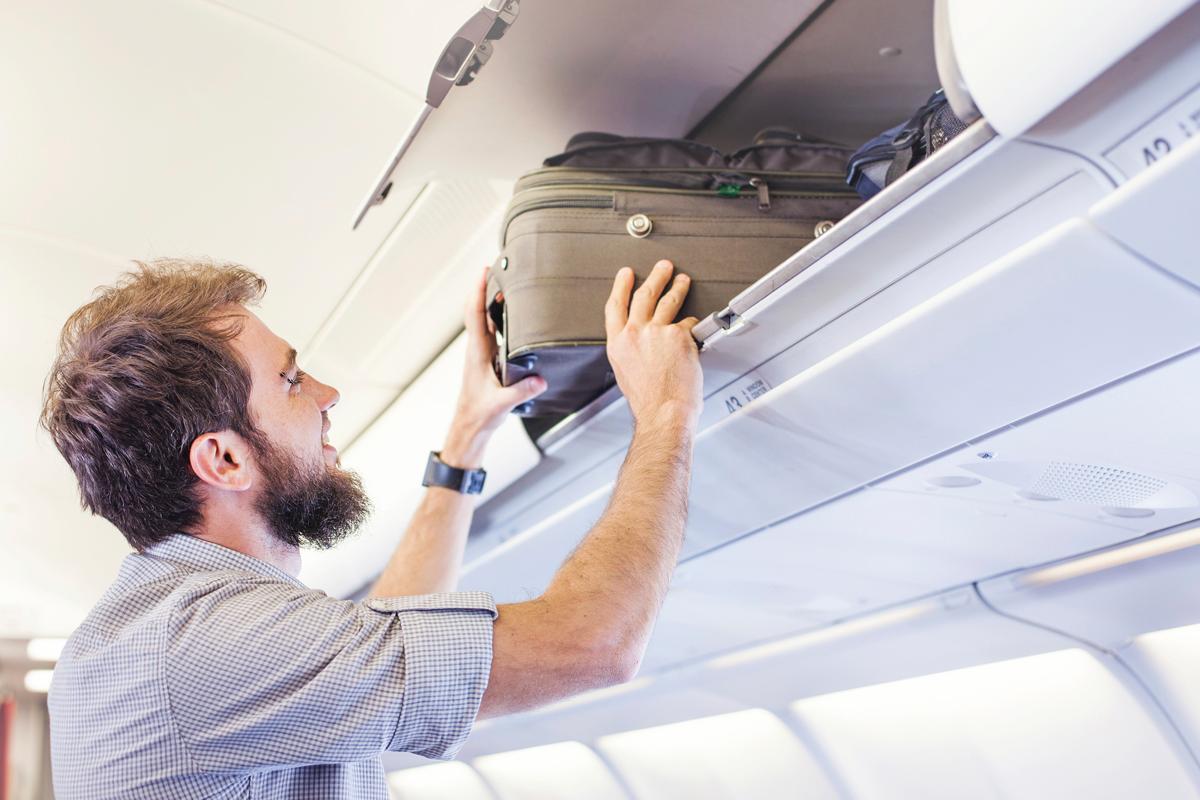 Fluggast schiebt Gepäck in Ablagefach