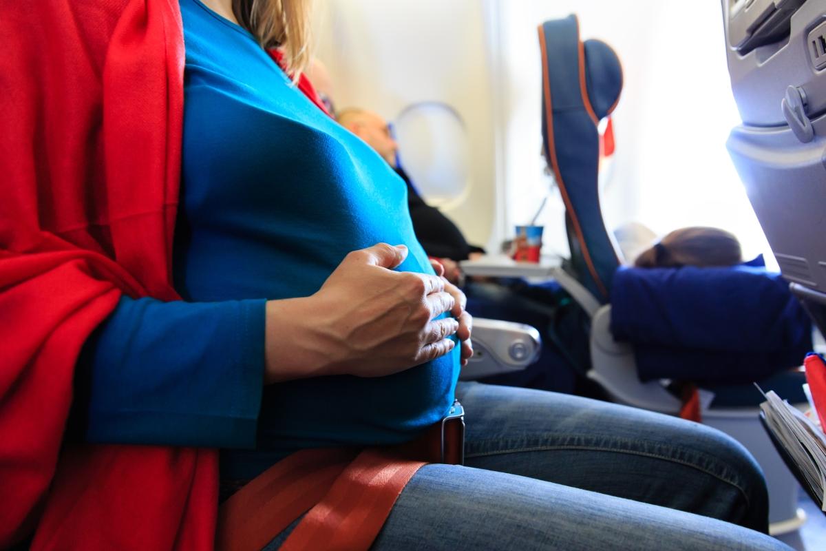 Seitlicher Blick auf eine schwangere Frau in einem Flugzeugsitz