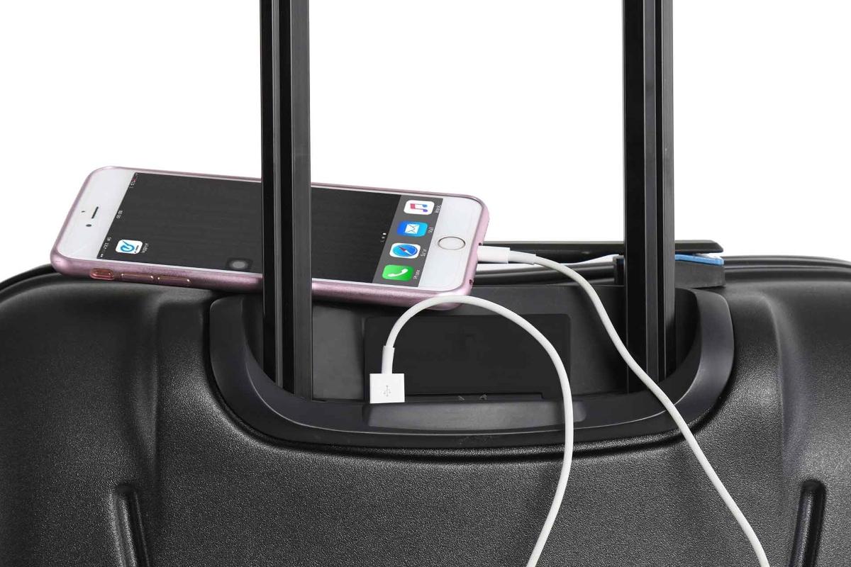 Trolley-Koffer, auf dem ein Handy liegt. Handy ist über Ladekabel mit Koffer verbunden.