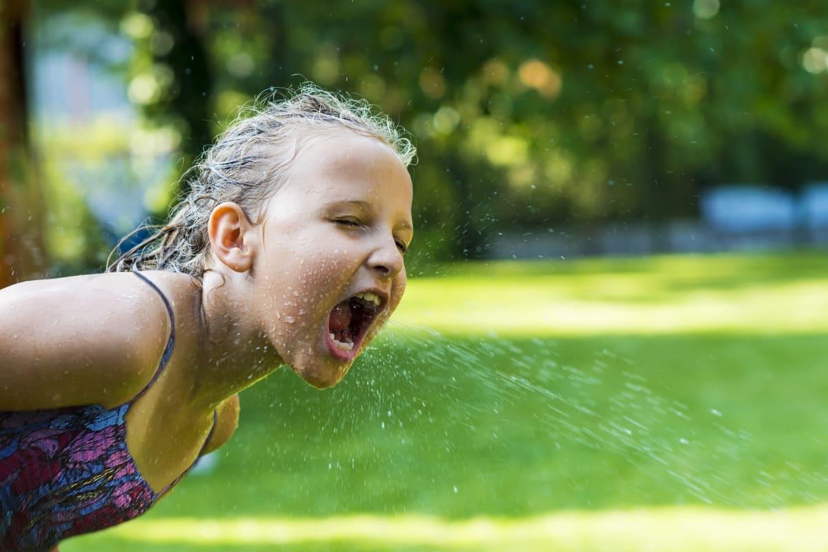 Mädchen trinkt Wasser aus Leitung